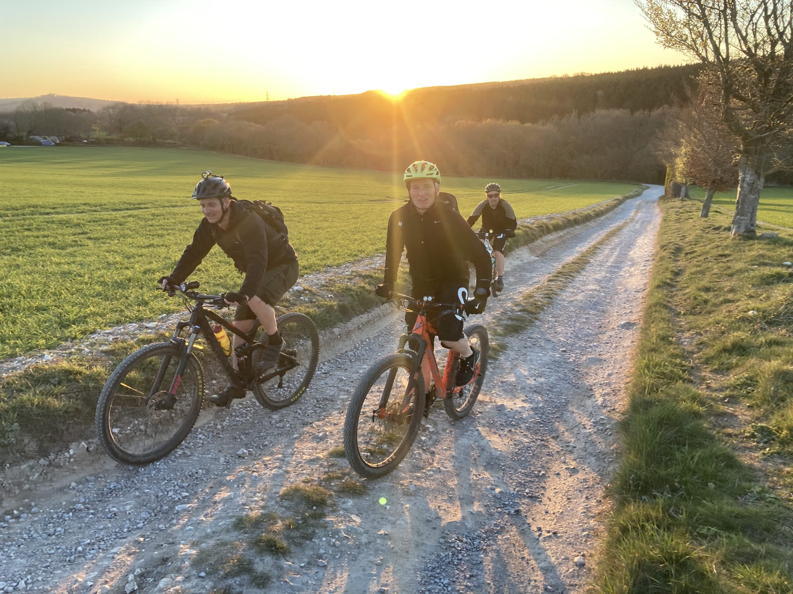 friends riding mountain bikes at sunset